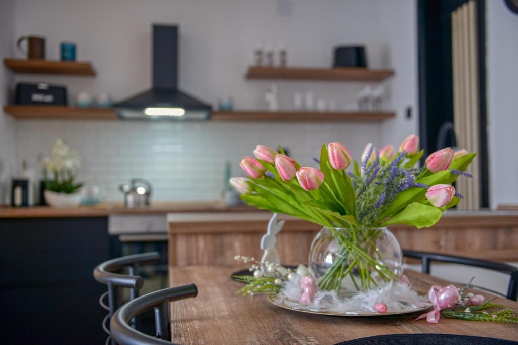 um vaso de flores cor-de-rosa numa mesa numa cozinha em Dream Apartment Vršac em Vršac