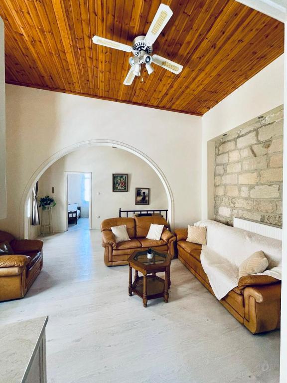 een woonkamer met banken en een plafondventilator bij Casa Dino Bello in Rhodos-stad