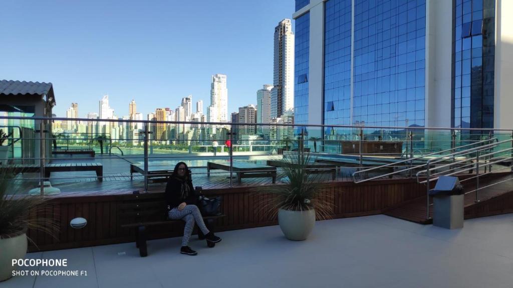 a woman sitting on a bench in a building at LOFT com garagem e piscina Prédio frente MAR in Balneário Camboriú