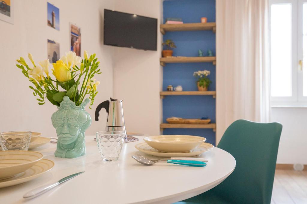 una mesa de comedor con un jarrón de flores. en La Petite Maison en Portoferraio