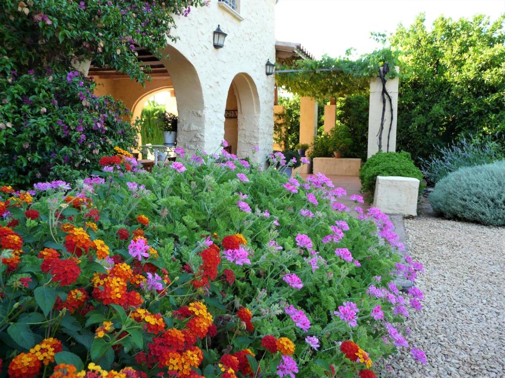 un giardino con fiori colorati di fronte a un edificio di Casa rural con encanto, 4 hab con 4 baños completos en suite, piscina y campo privado a Pedreguer
