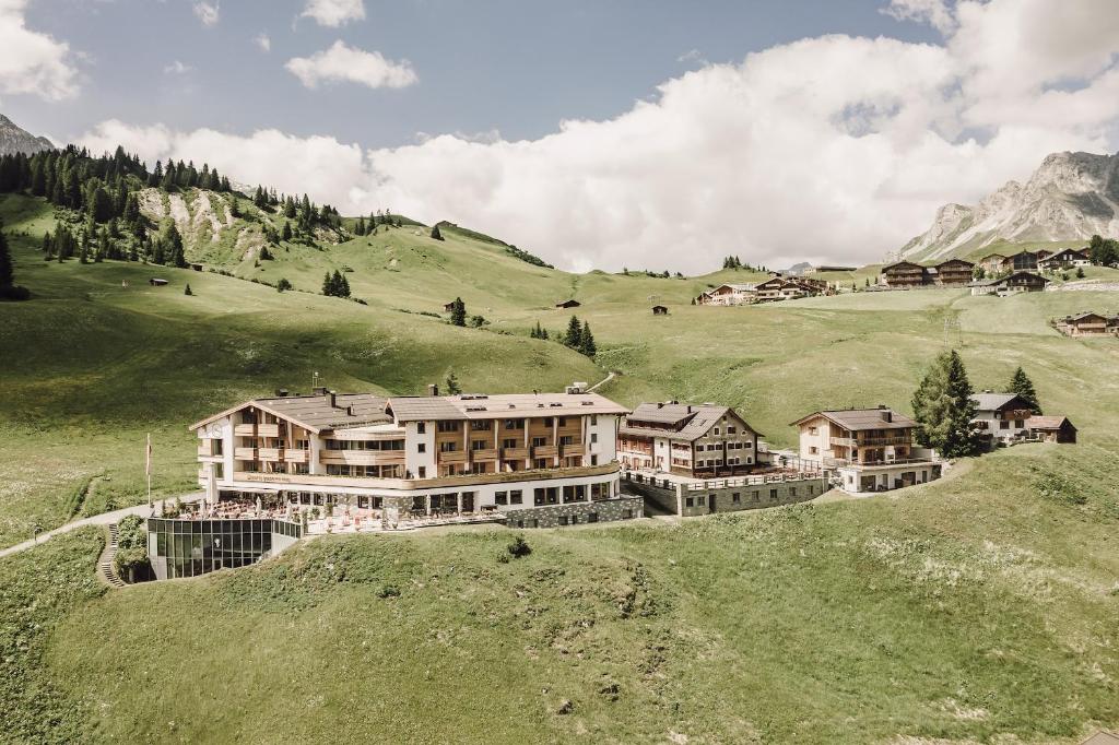 un grand bâtiment sur une colline dans un champ verdoyant dans l'établissement Hotel Goldener Berg, à Lech am Arlberg