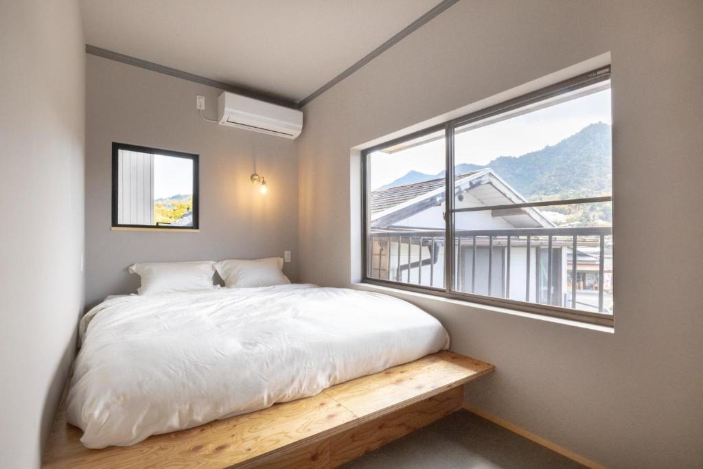 a bedroom with a bed and a large window at Coliving & Cafe SANDO - Vacation STAY 27354v in Imabari