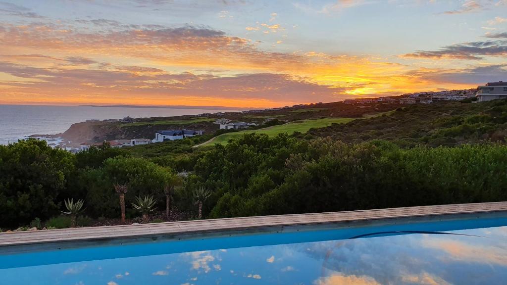 una piscina con vista sull'oceano al tramonto di Luxury Home located on Pinnacle Point Golf Estate a Mossel Bay