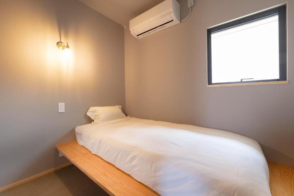 a small bedroom with a white bed and a window at Coliving & Cafe SANDO - Vacation STAY 27347v in Imabari