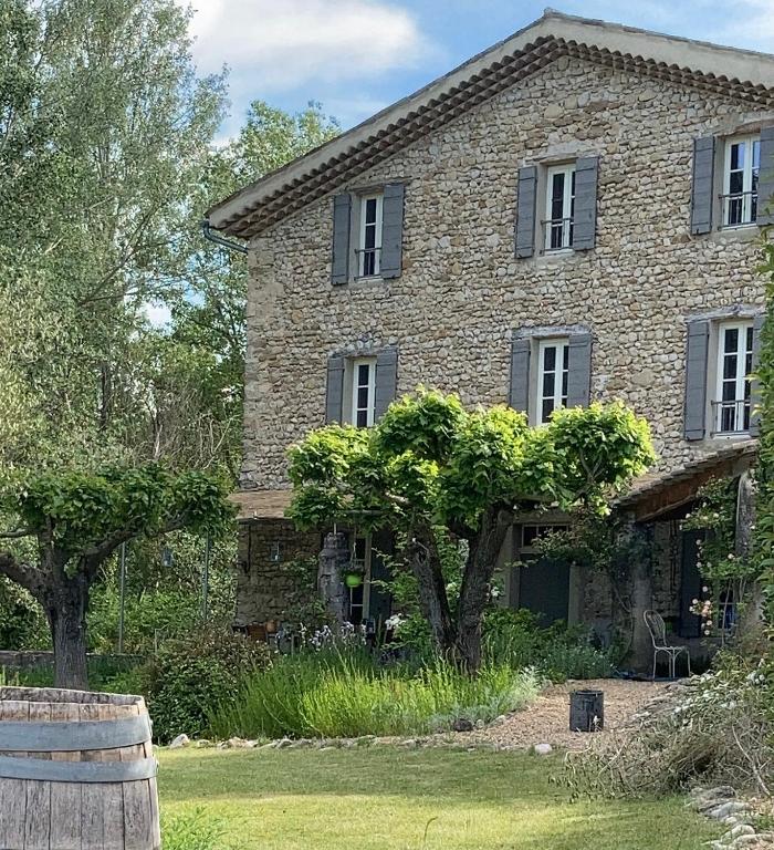 une maison en pierre avec un arbre devant dans l'établissement Mas Lou Parpaioun, à Crestet