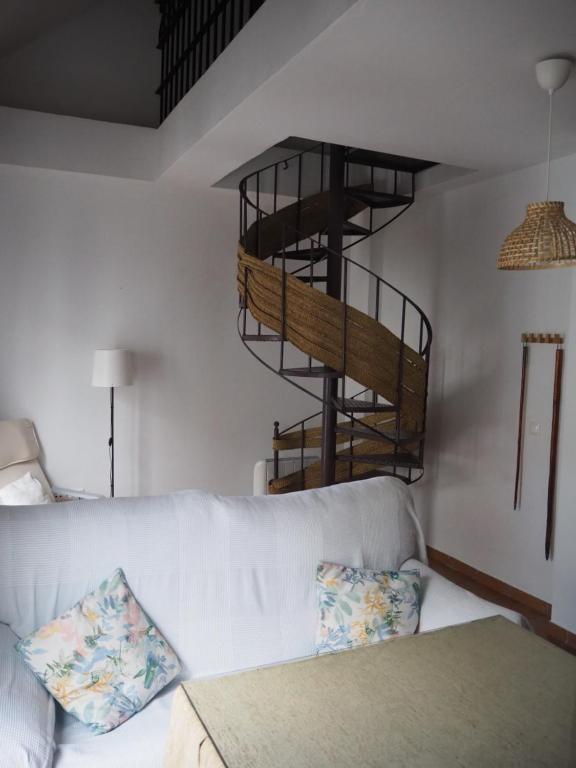 sala de estar con sofá blanco y escalera de caracol en Sendero de la Subbetica - Apartamentos Turisticos en Zuheros - Holiday Home, en Zuheros