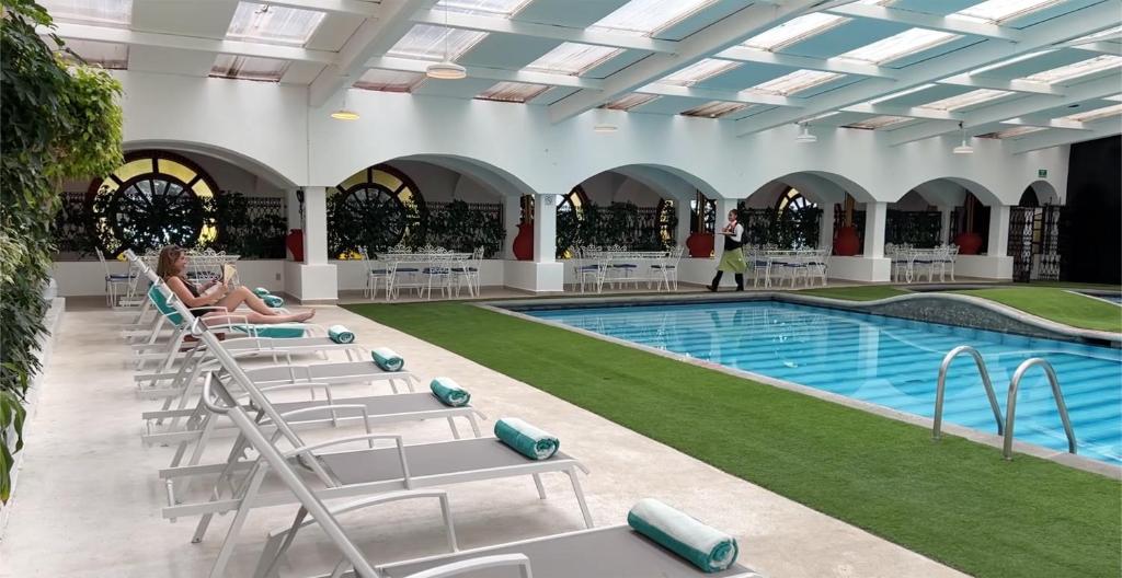 a woman sitting on lounge chairs next to a swimming pool at GS Jerocs Tlaxcala in Tlaxcala de Xicohténcatl