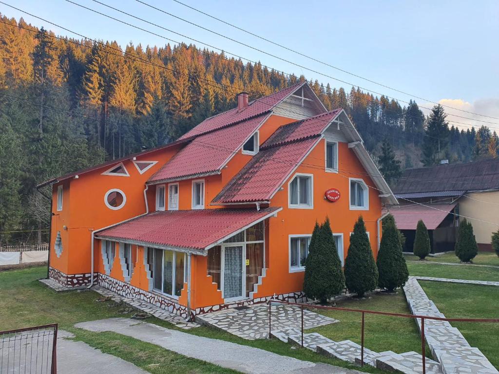 una casa naranja con techo rojo en Pensiunea Marydor, en Gârda de Sus