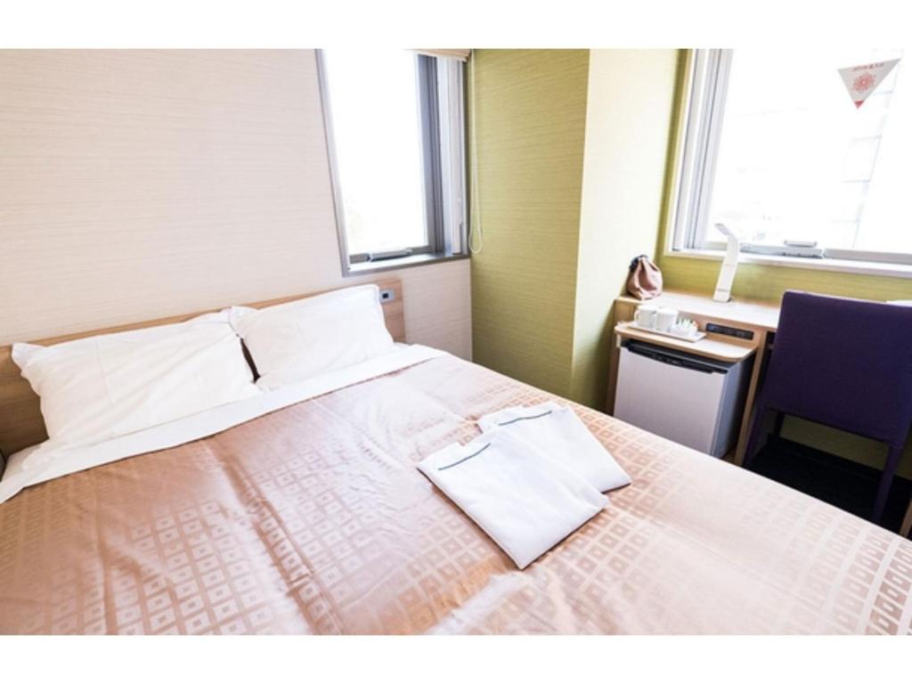 a hotel room with a bed with white sheets and a window at Meet Inn Narita - Vacation STAY 43769v in Narita
