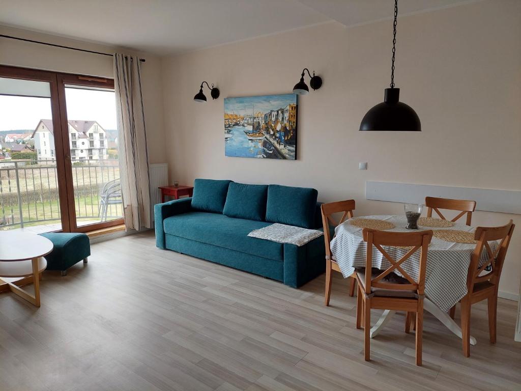 a living room with a blue couch and a table at Bursztynowy 1 in Karwia