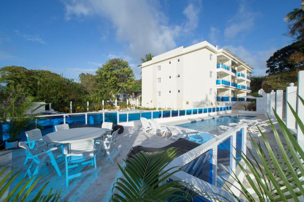 een zwembad met een tafel en stoelen naast een gebouw bij CoralK Apartments Sosúa in Sosúa