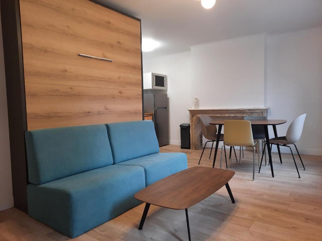 un salon avec un canapé bleu et une table dans l'établissement Résidence Beauvau - Numéro 6 - Centre de SARLAT, à Sarlat-la-Canéda