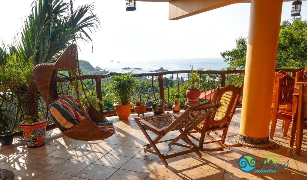 a patio with chairs and a view of the ocean at Cabañas Telayú in Mazunte
