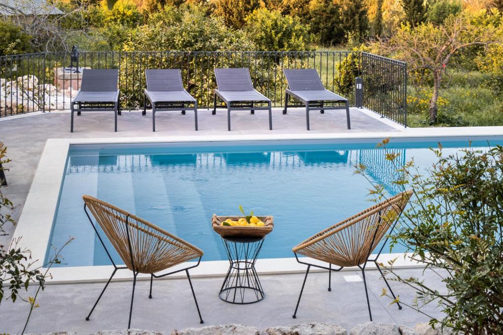 einen Pool mit Stühlen, einem Tisch und einer Obstschale in der Unterkunft Masseria Bio - Agriturismo Villa Grazia in Avola