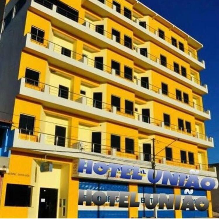 a large yellow building with a hotel sign in front of it at Hotel União in Pojuca