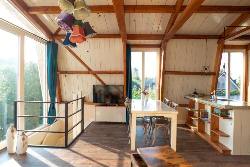 een kamer met een tafel, een tv en ramen bij klein polderhuis - bollenschuur in Roelofarendsveen