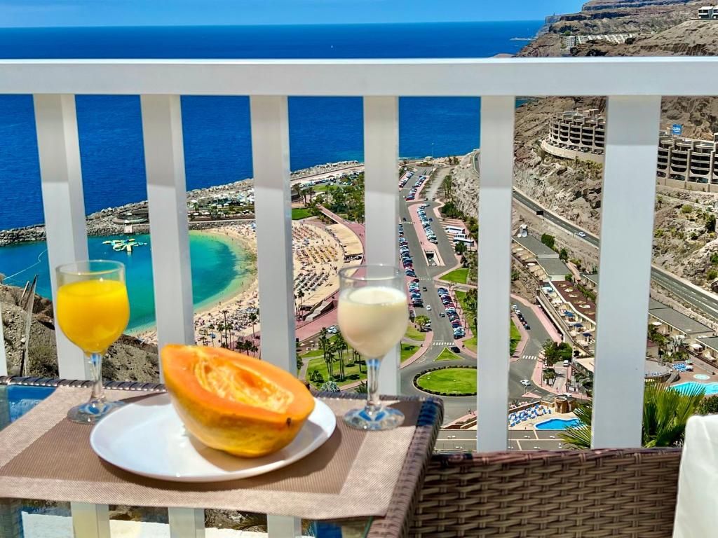 a table with two glasses of oranges and a view of the ocean at Canarias Sunshine Amadores in Amadores