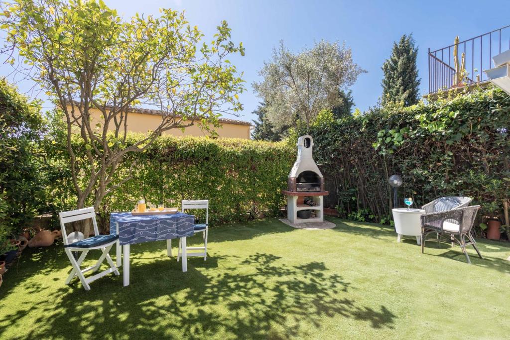 um quintal com uma mesa e cadeiras e um grelhador em Bonita casa adosada con jardín privado y piscina comunitaria em Calella de Palafrugell