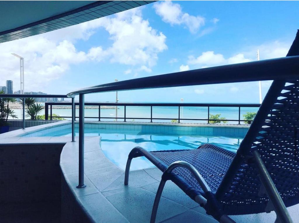 uma piscina com um banco e vista para o oceano em Apê Beira Mar Meireles Com café da manhã em Fortaleza