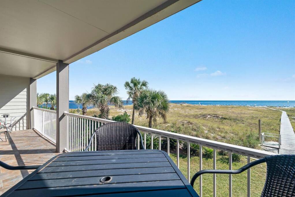 a porch with a table and chairs and the ocean at Summer Breeze #25 - Modest Beachfront with views of the Pass! Great Location! in Orange Beach