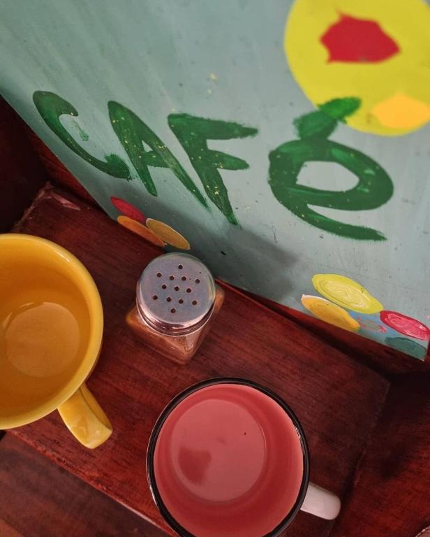 a wooden table with two cups and a book at Tatami Hostel in Bucaramanga