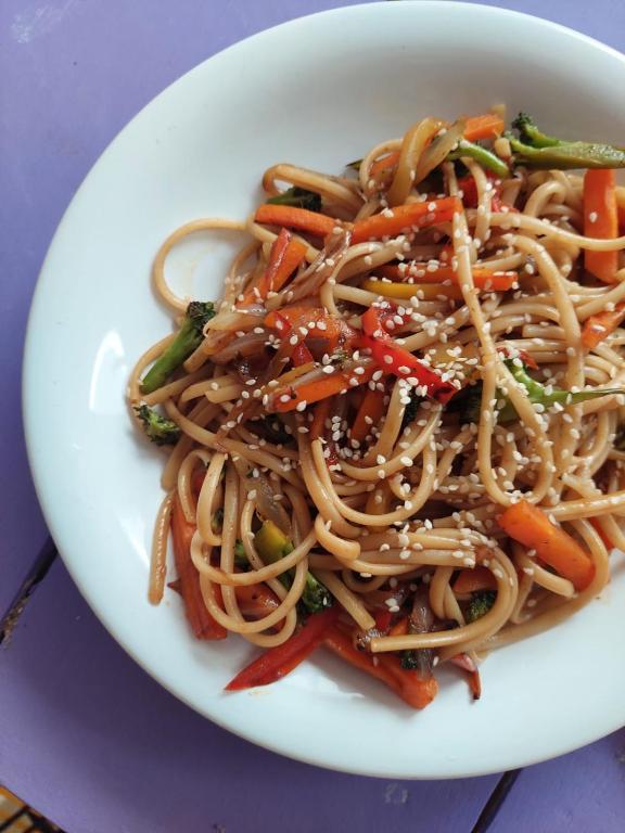 a white plate of food with noodles and vegetables at Tatami Hostel in Bucaramanga