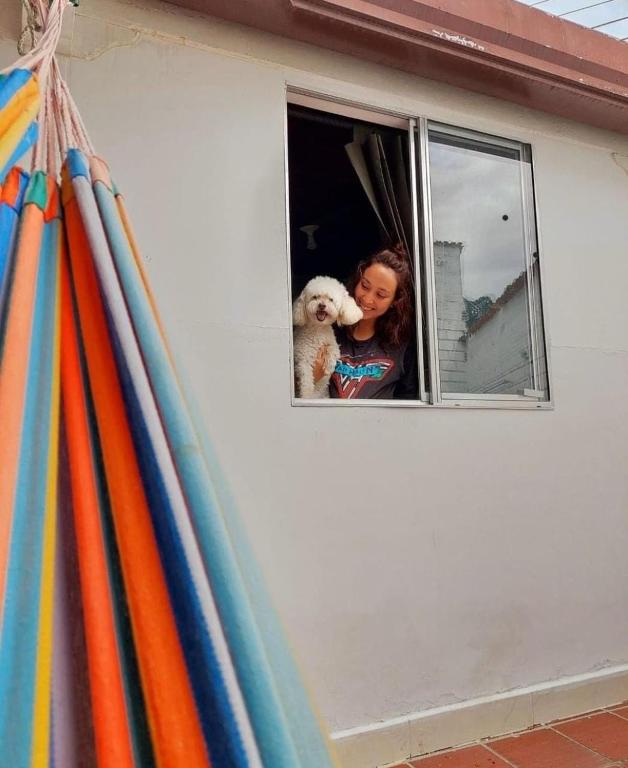 a woman with a dog looking out of a window at Tatami Hostel in Bucaramanga