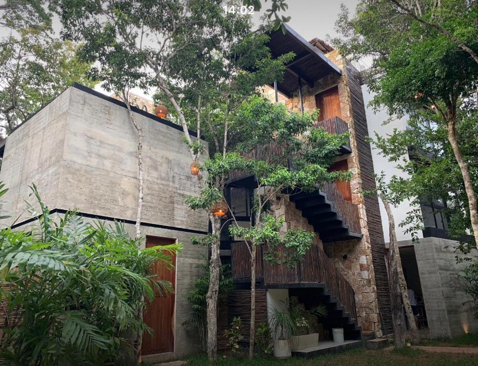 a brick house with a balcony and trees at La Casa de María 11:11 in Chemuyil