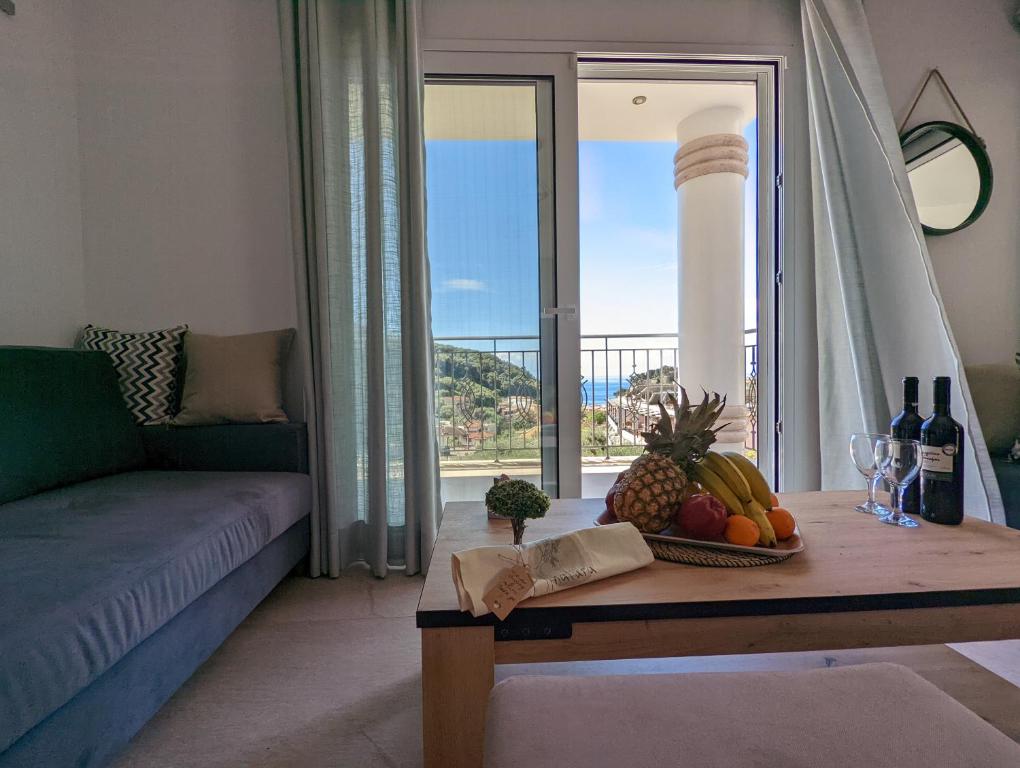 una sala de estar con una mesa con frutas y botellas de vino en Natura Luxury Suites Parga, en Parga