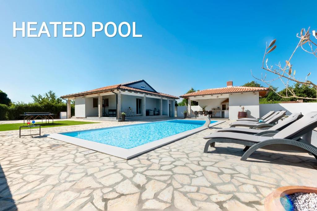 een zwembad met stoelen en een huis bij Villa Miracolo in Rovinj