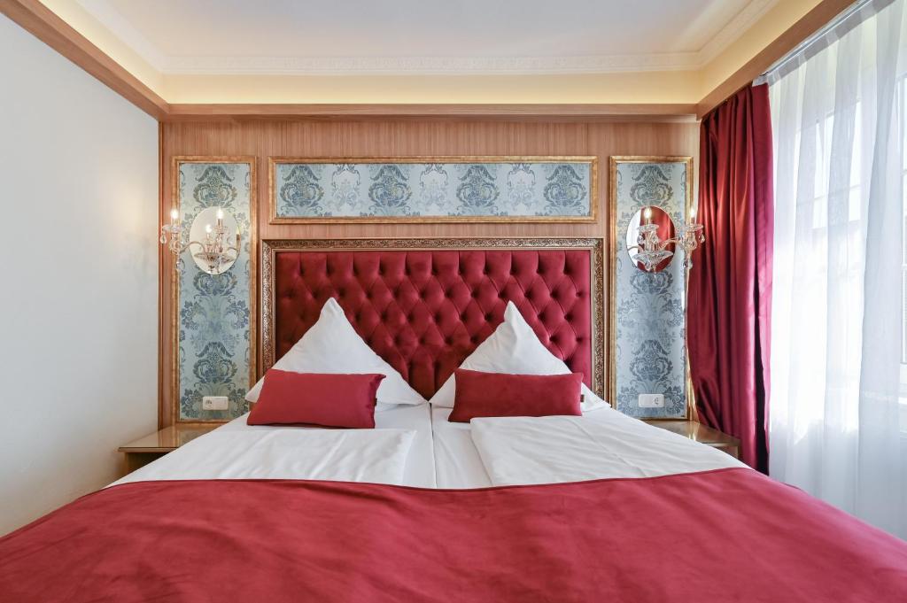 a bedroom with a red and white bed with red pillows at Hotel Ludwigs in Füssen