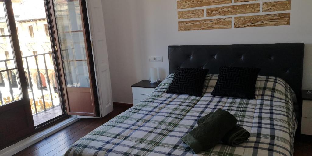 a bedroom with a bed with a checkered blanket at Apartamentos Plaza Mayor in León