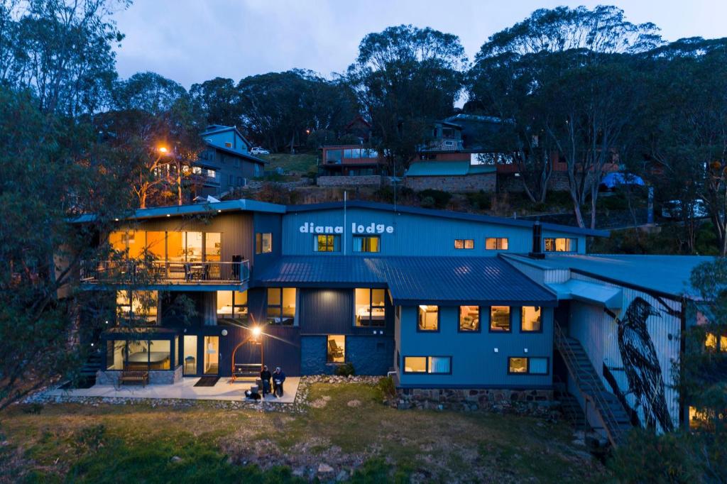 a large blue house with its lights on at Diana Alpine Lodge in Falls Creek