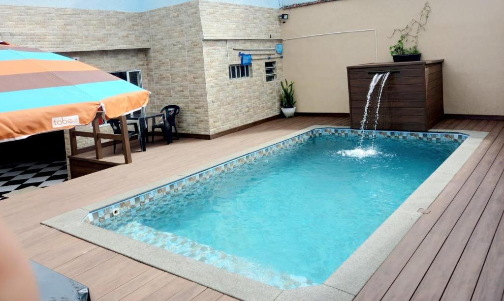 una piscina con una sombrilla en una terraza en Pousada Zambeze, en Praia Grande