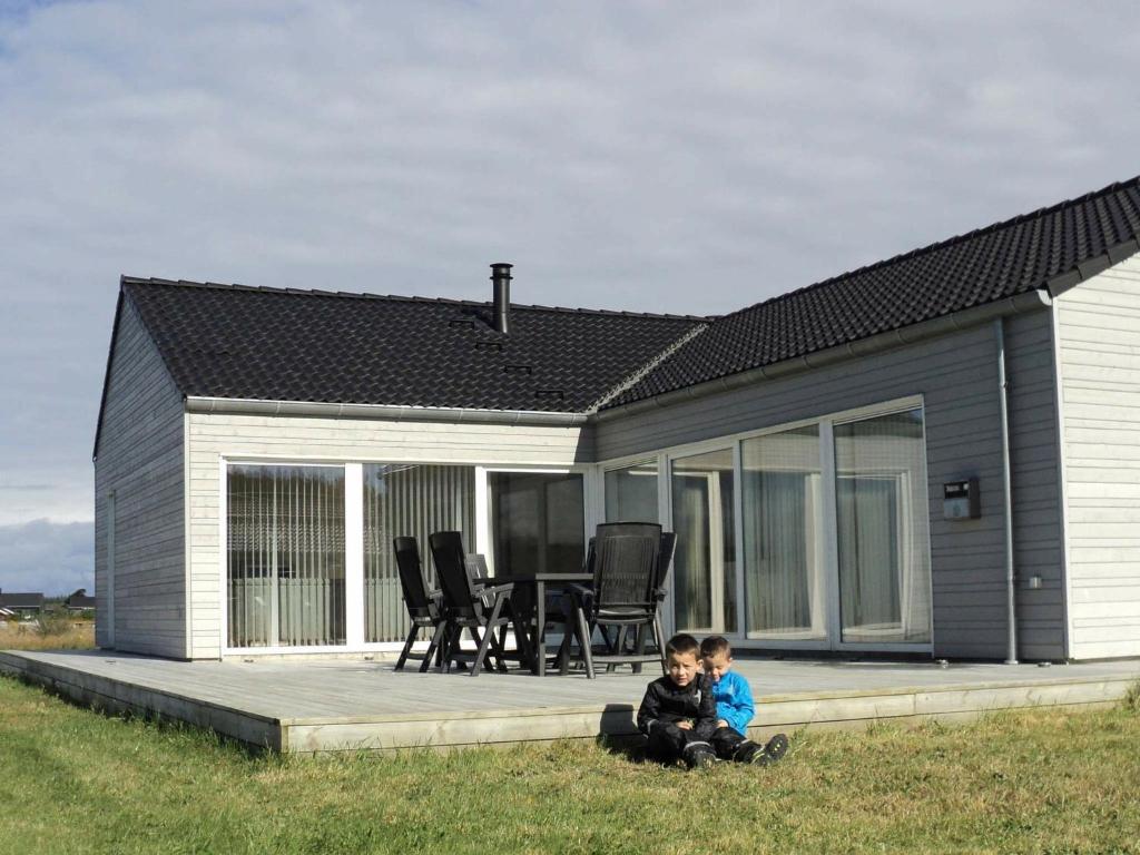 dos niños sentados en el césped frente a una casa en 10 person holiday home in Brovst, en Brovst