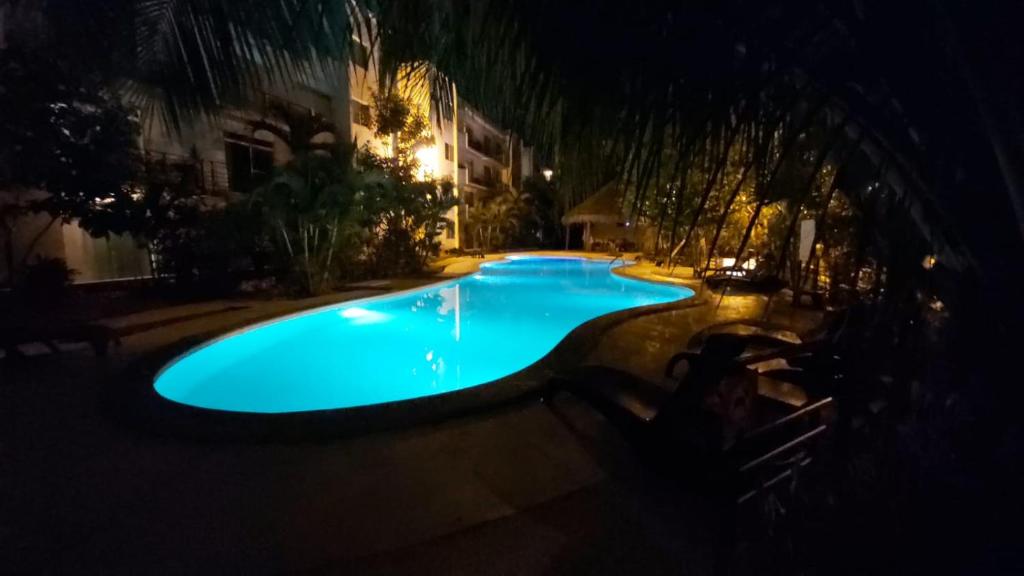 a swimming pool at night with a blue pool at Beach Castell Suites in Playa del Carmen