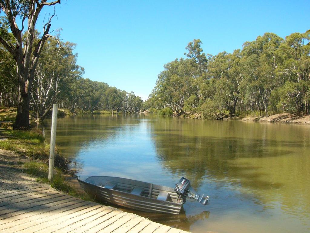 a small boat sitting on the side of a river at Deniliquin Riverside Caravan Park in Deniliquin