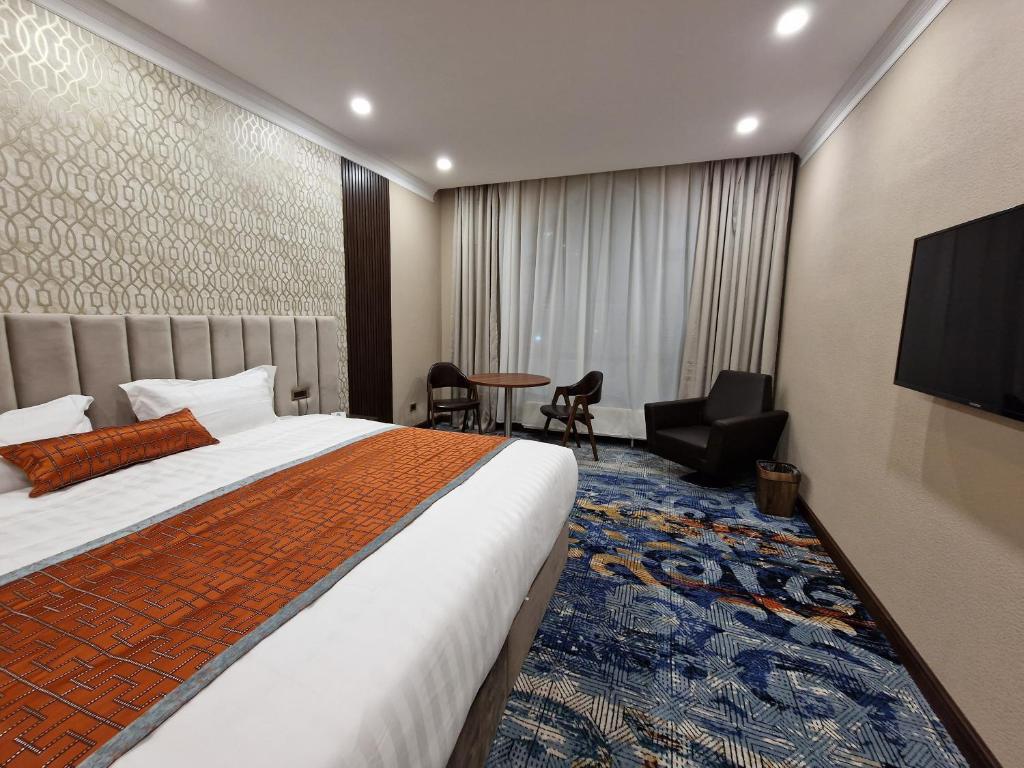 um quarto de hotel com uma cama e uma televisão em New West Hotel em Ulan Bator