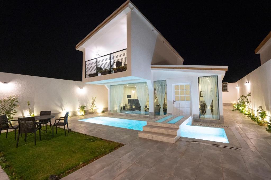 a villa with a swimming pool at night at Divon Chalets in Buraydah