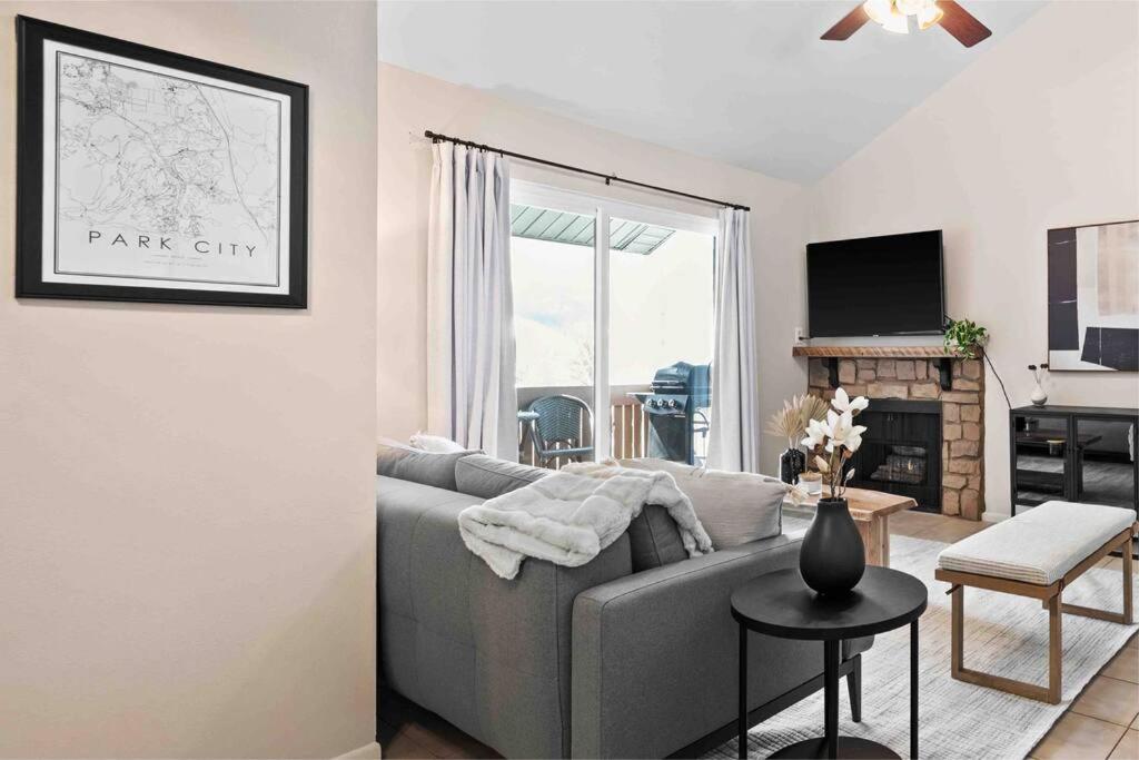 ein Wohnzimmer mit einem grauen Sofa und einem Tisch in der Unterkunft Cozy Top Floor Condo with Mountain Views in Park City