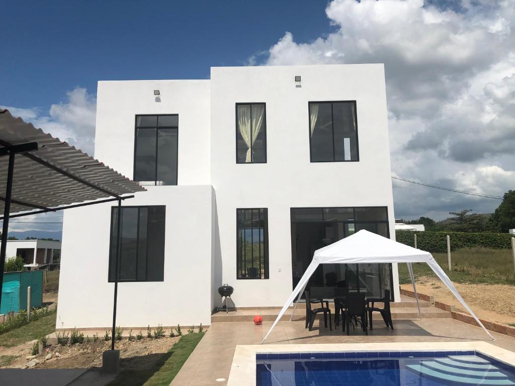 ein weißes Haus mit einem Pool davor in der Unterkunft Villa privada en condominio San Simon in Carmen de Apicalá