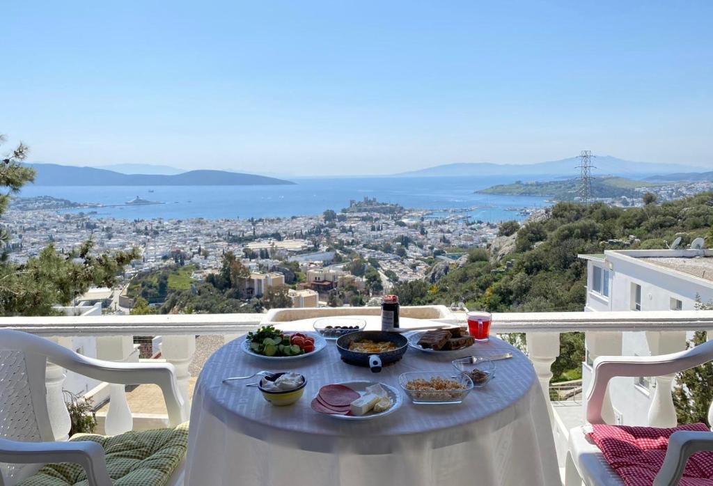 - une table avec de la nourriture sur un balcon avec vue sur la ville dans l'établissement BODRUM BURCU VILLA , Magnificent Sea View, Cozy, Free Otopark, Free Wifi, à Bodrum City