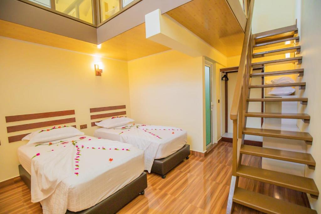 two beds in a room with a ladder at Relax Villa in Thoddoo