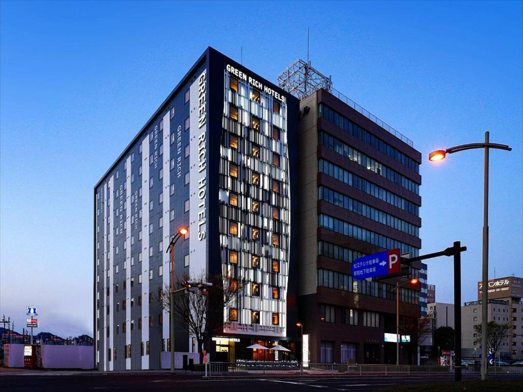 a tall building on the corner of a street at Green Rich Hotel Matsue Station Across - Artificial hot spring Futamata Yunohana in Matsue