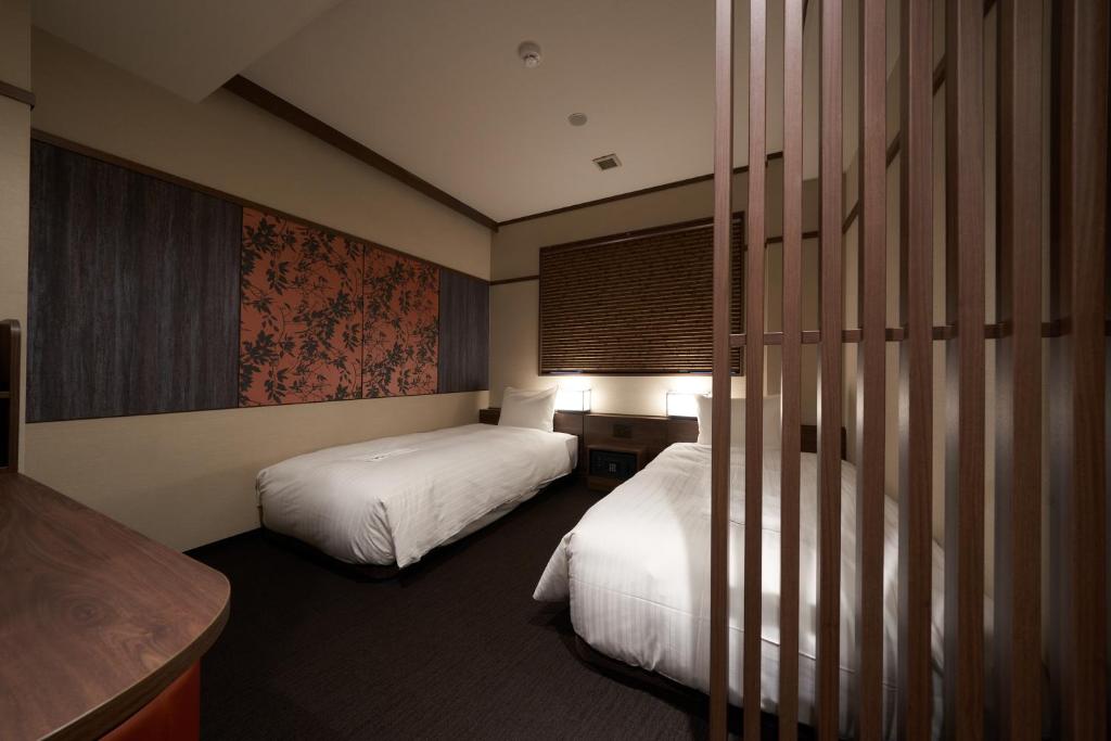 大阪市にあるWelina Hotel Shinsaibashi NAGOMIのベッド2台とテーブルがあるホテルの部屋