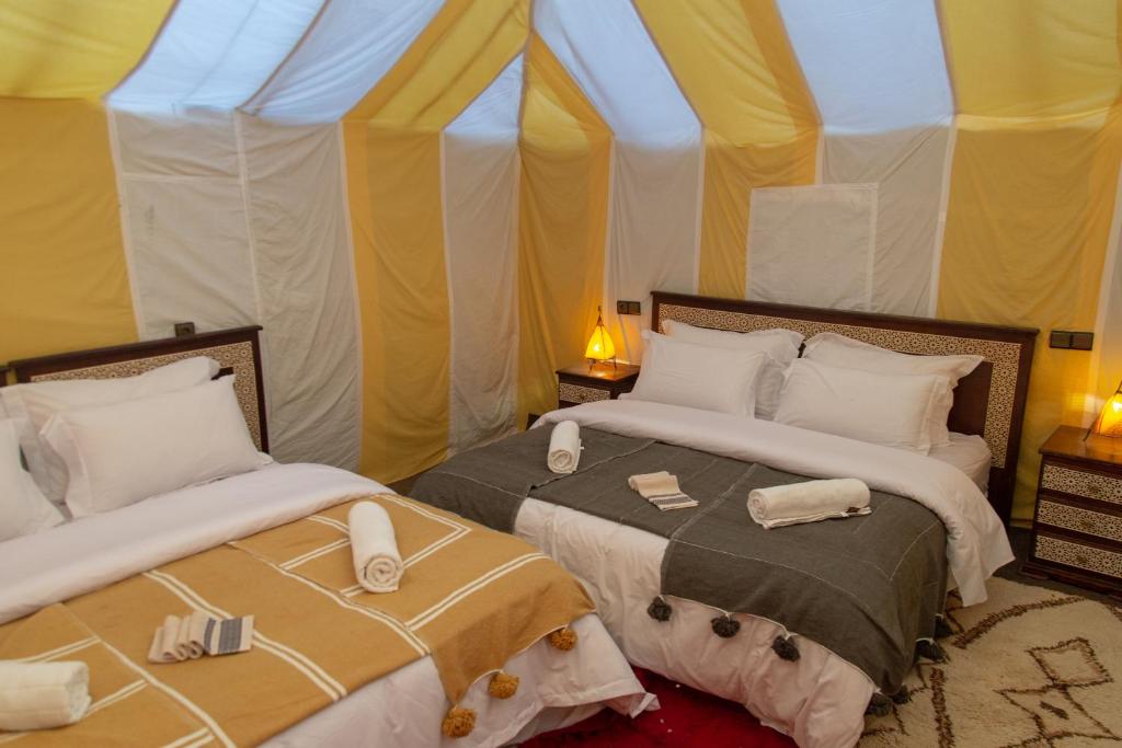two beds in a room with a tent at Merzouga Premium Desert Camps in Merzouga