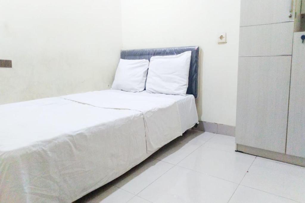 1 cama blanca con sábanas y almohadas blancas en una habitación en SPOT ON 91161 Pondok Jaya Syariah, en Bandung