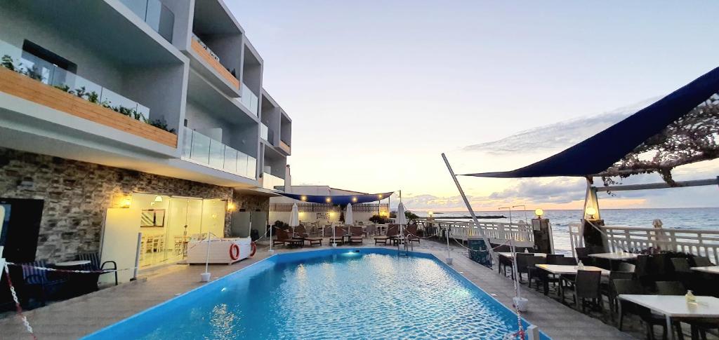 een hotel met een zwembad met tafels en stoelen bij Sunset Beach Hotel in Kokkíni Khánion