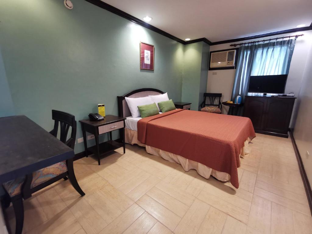 a bedroom with a bed and a table and a table at Tagaytay Country Hotel in Tagaytay